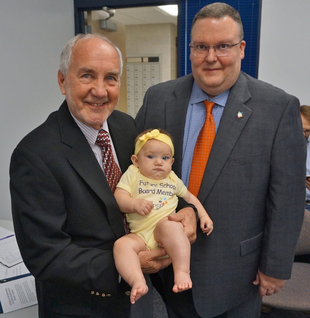 Board member holding grandchild.