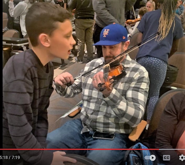 Photo of students and parents learning to play an instrument.