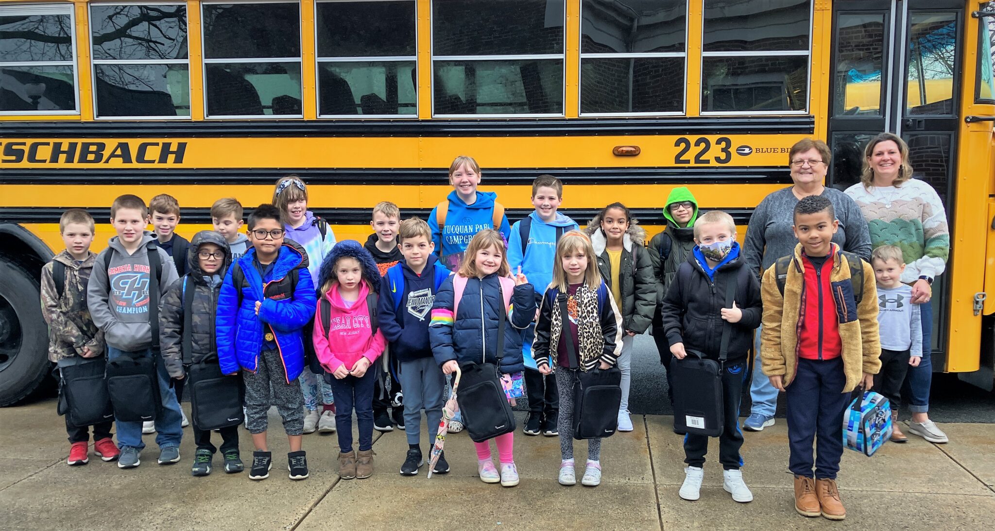 Photo of former bus driver Rowe Kenneson with her bus and students.