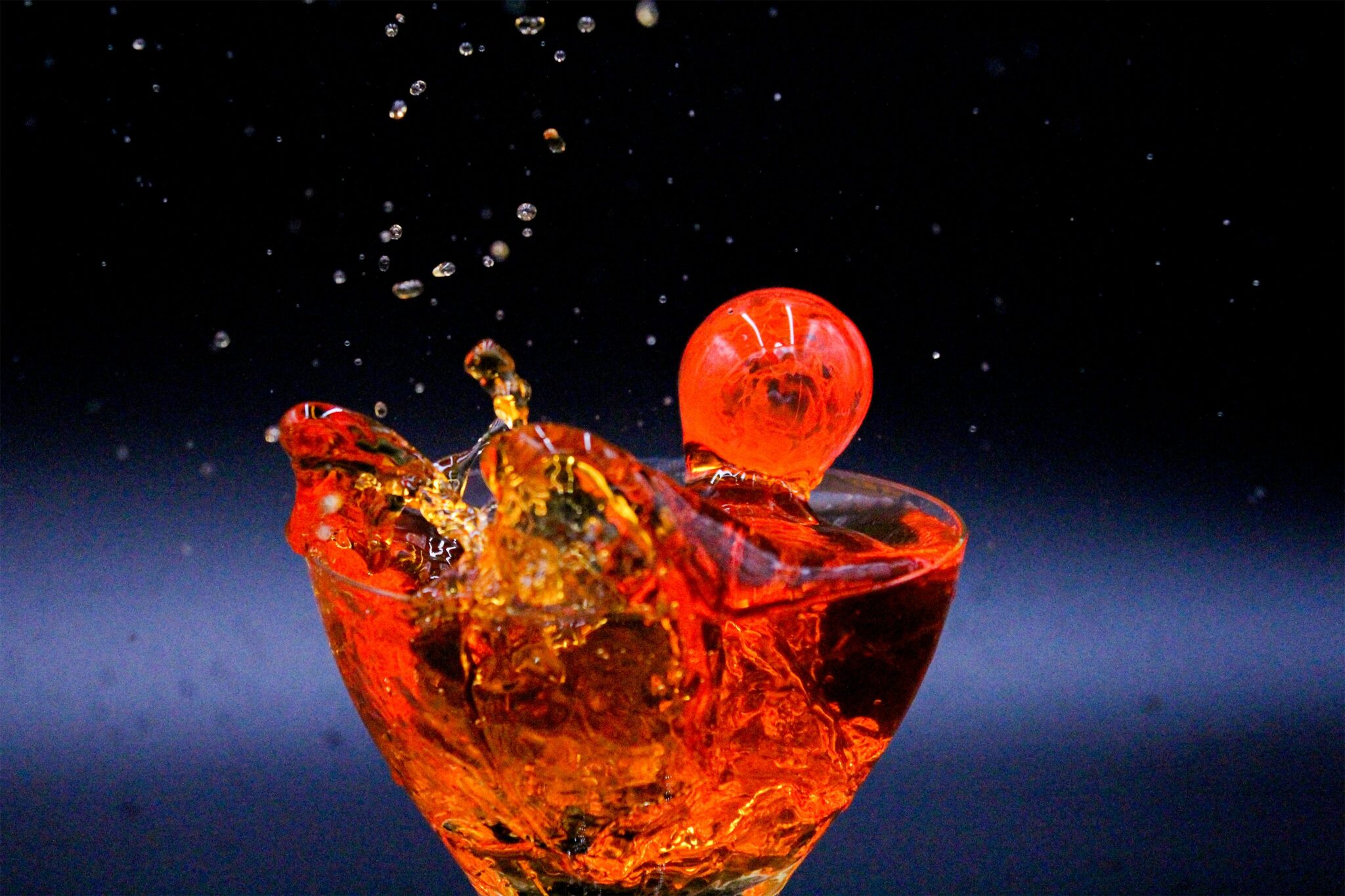 A photo of a cherry dropping into a drink
