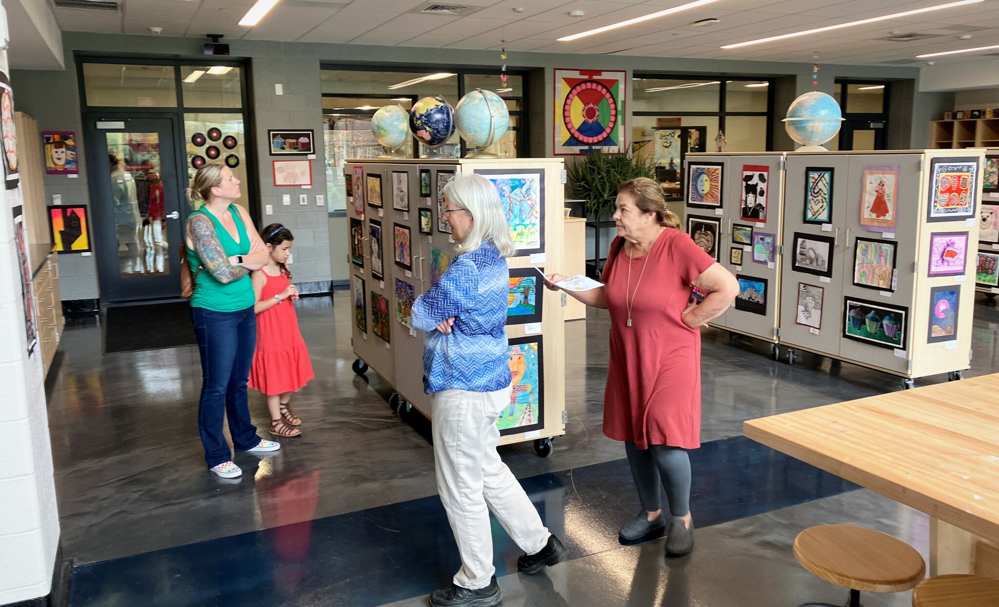 Photo of four people viewing student artwork in the high school art studio