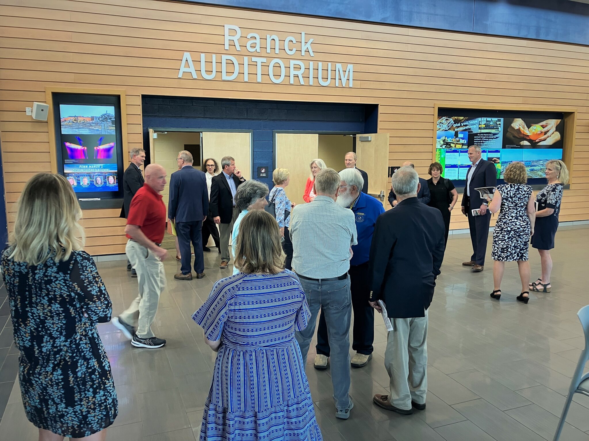 Photo of several people socializing outside the auditorium at Penn Manor High School.