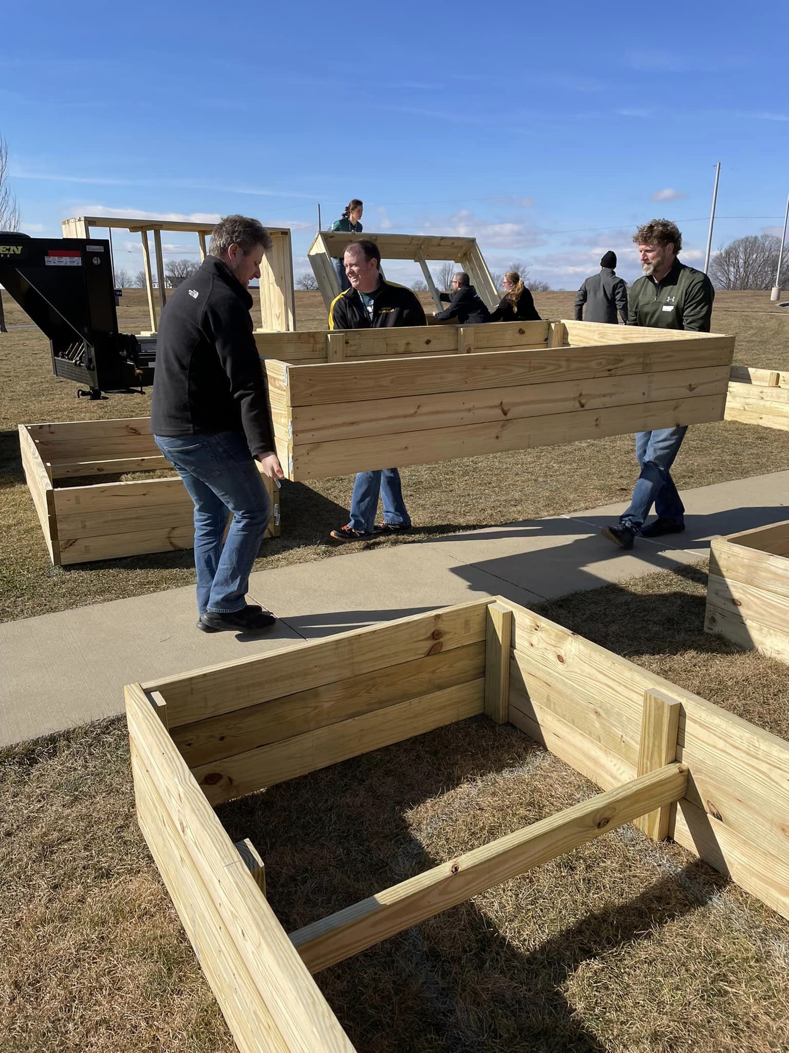 Photo of teachers carrying empty beds at the garden site.