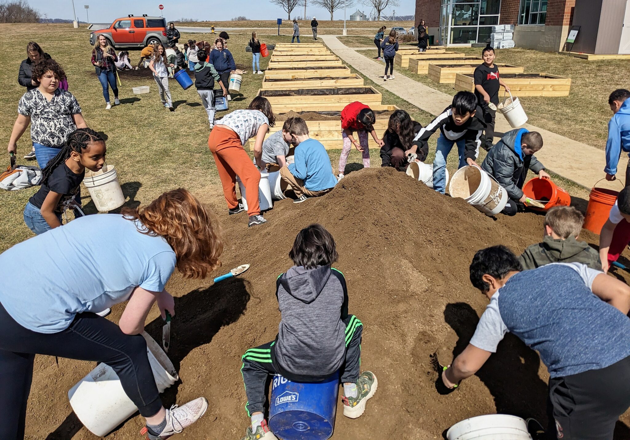 Photo of students gathering topsoil to fill the garden beds