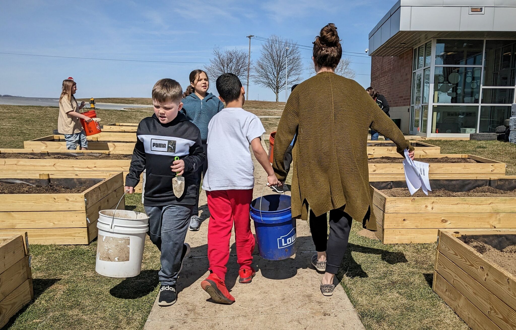 Photo of students and staff carrying soil in buckets