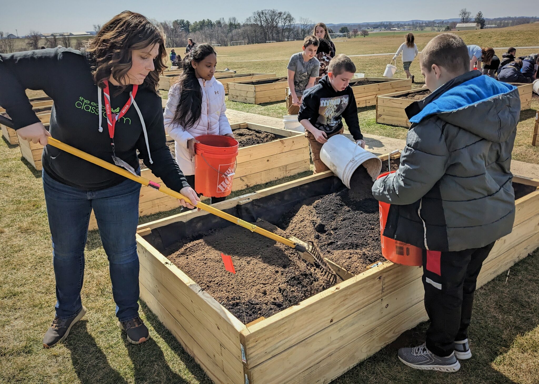 Photo of students and staff spreading soil in the garden beds