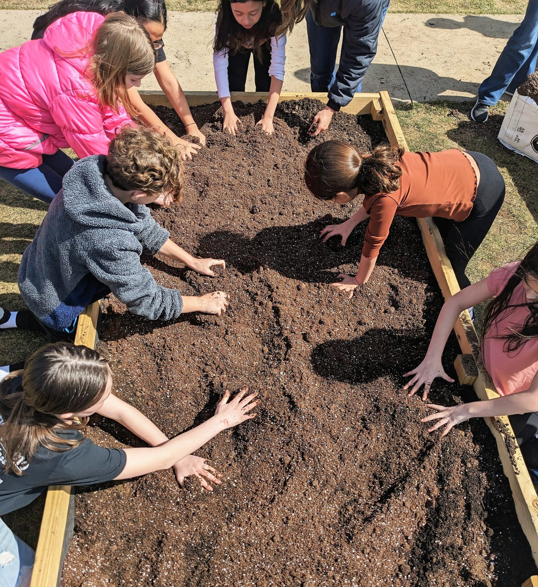 Photo of students breaking up soil in the garden beds.