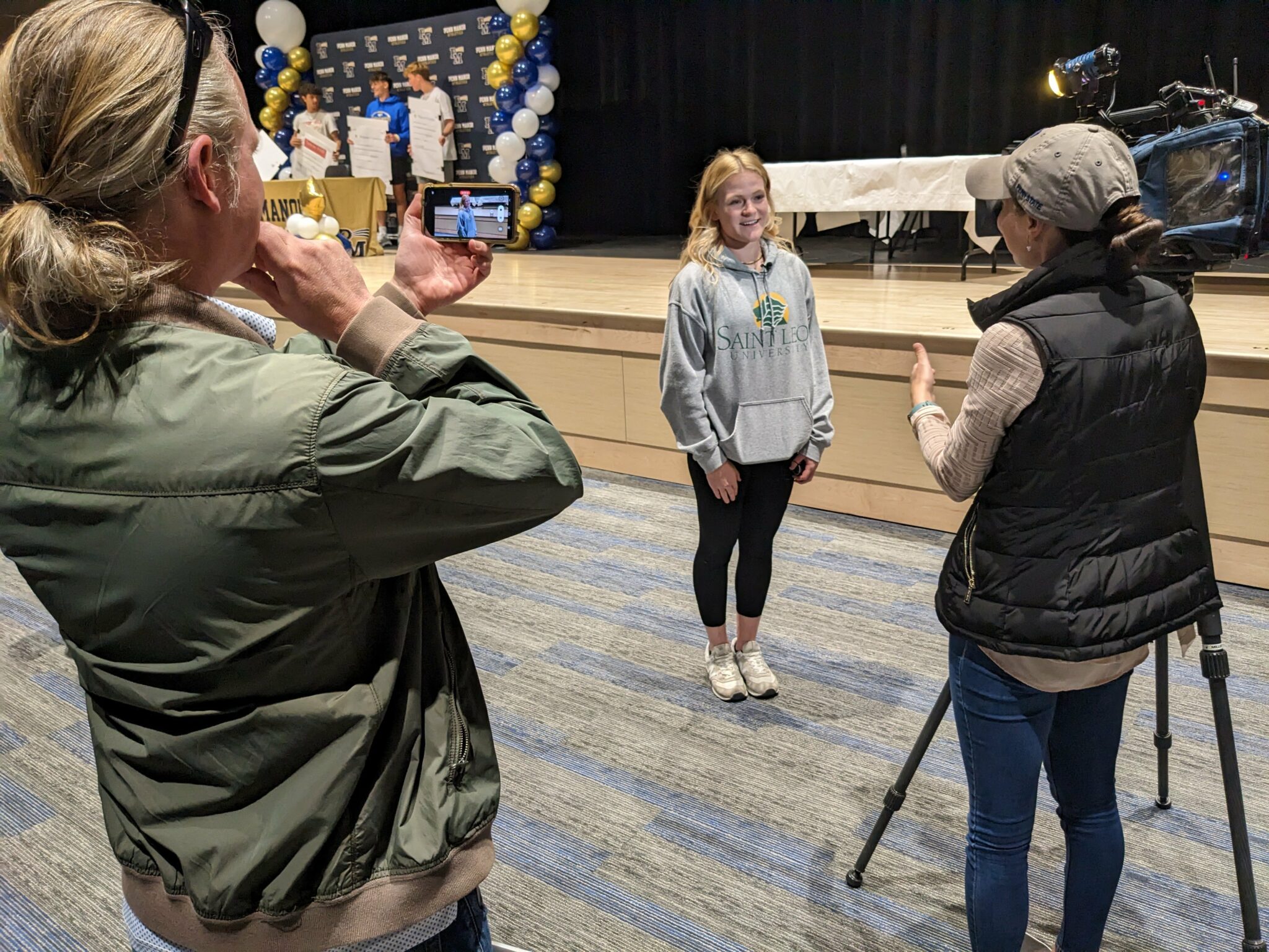A member of the news media interviews a student athlete.