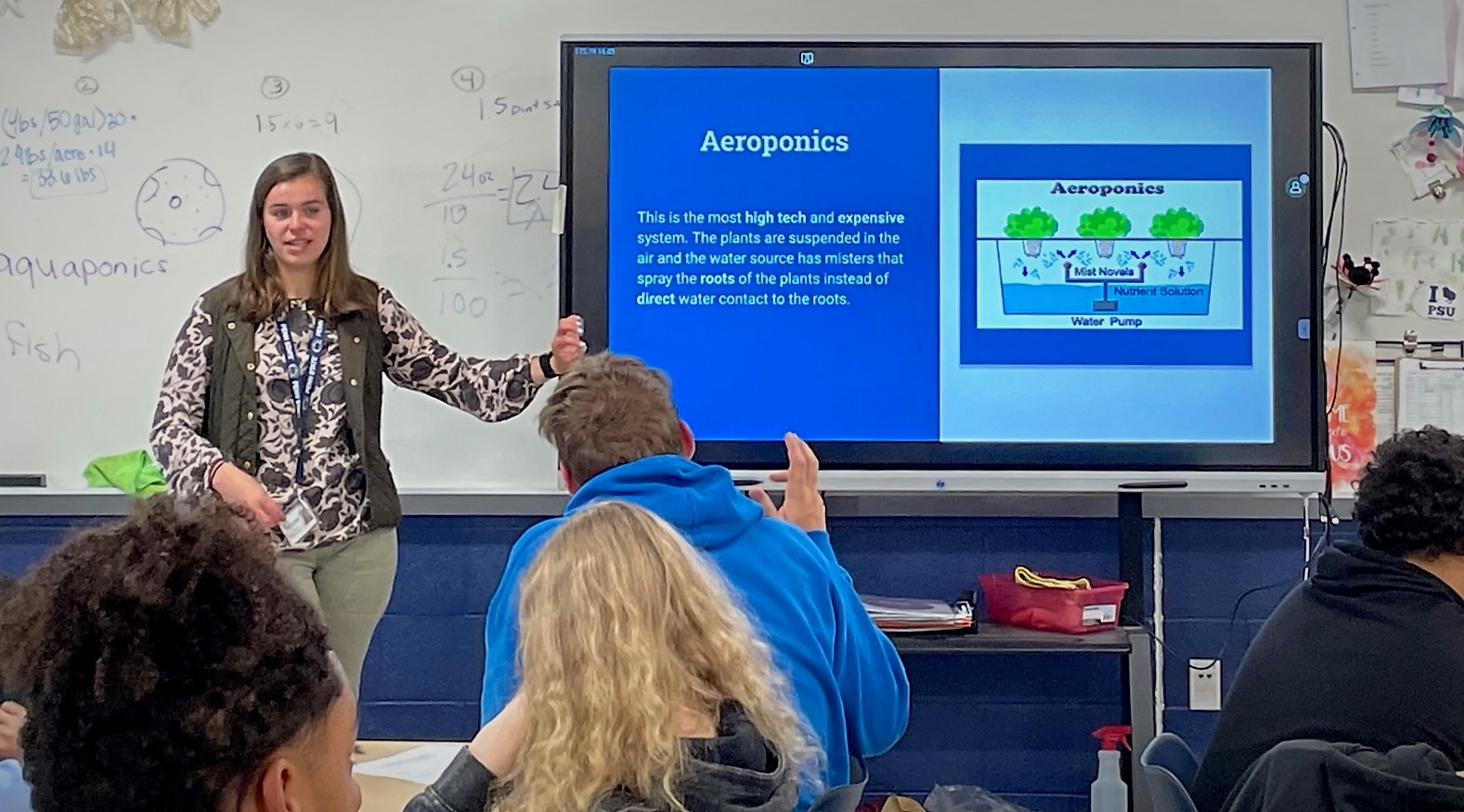 Photo of a teacher showing a slide to several students.
