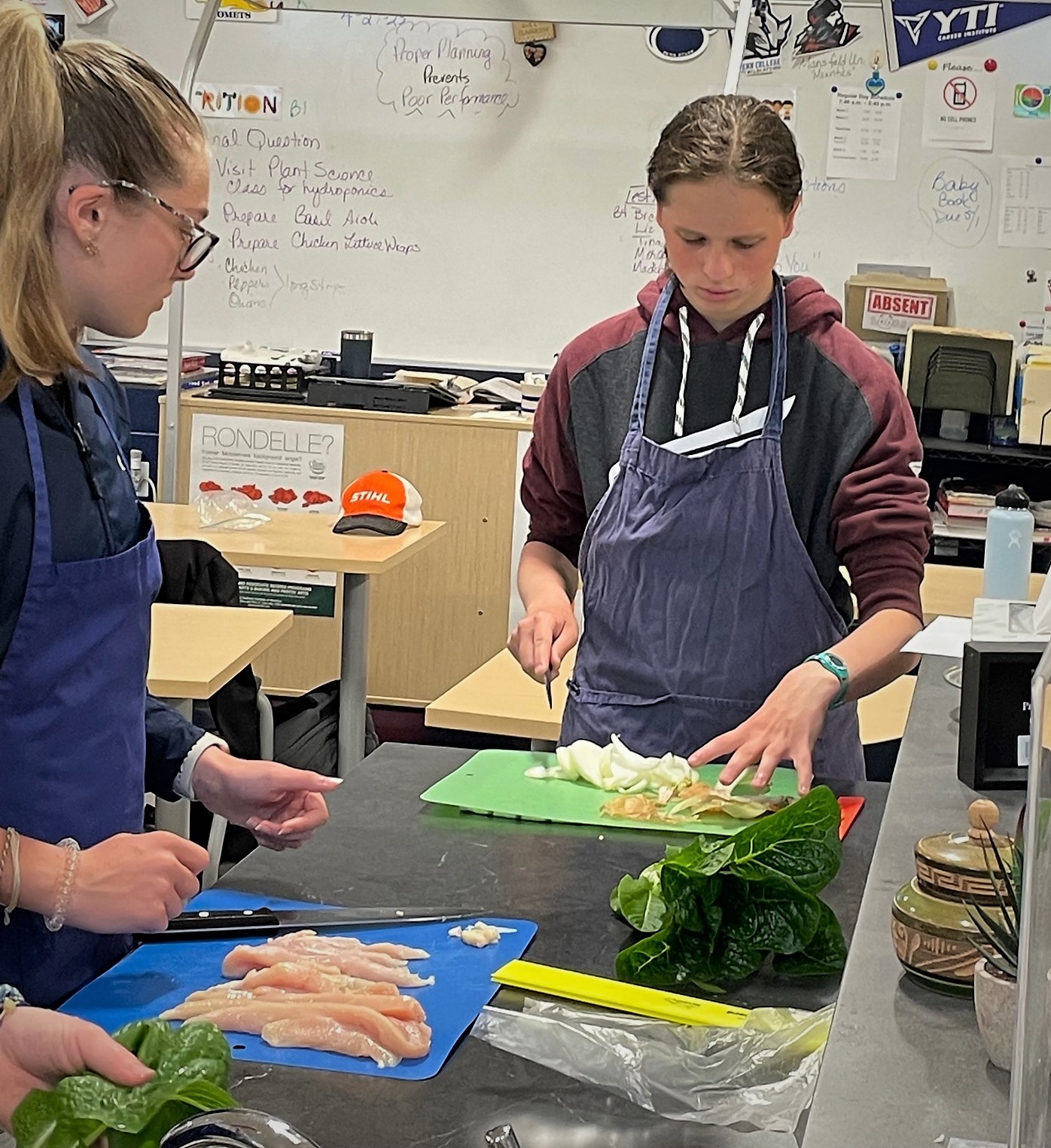 Photo of two students preparing chicken and vegetables.